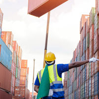Worker Directing Crane Stacking Cargo Containers 