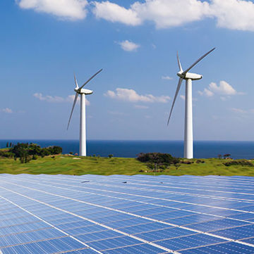 Photo of solar panel array on ground surrounded by windmills