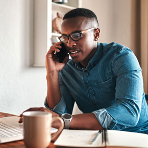 Man On Mobile Phone Looking At Laptop 