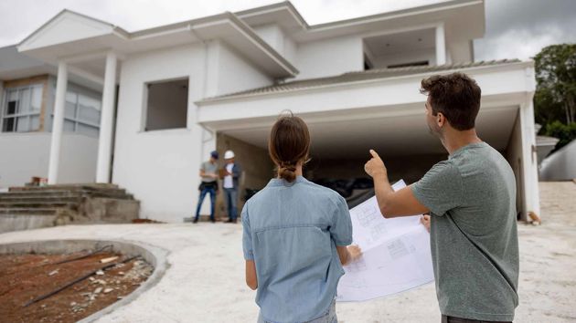 Man And Woman Looking At House Under Construction 