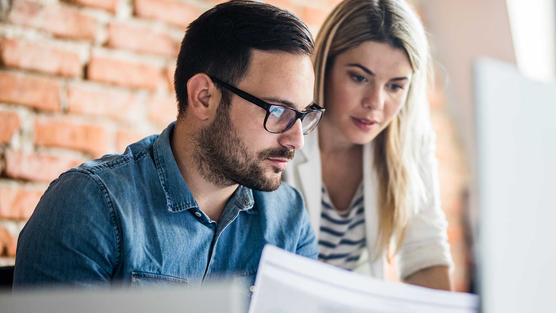 Coworkers Reviewing Data On Screen In Office 