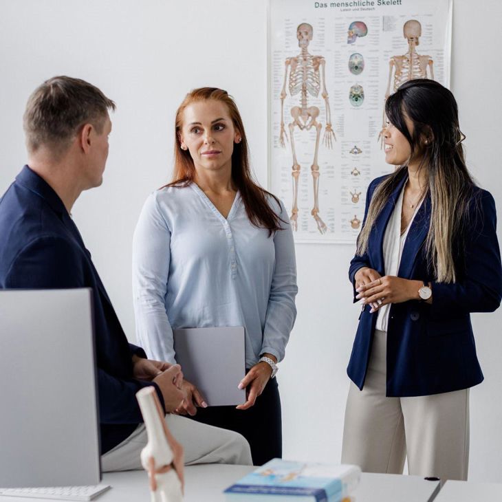 Three People Standing In Front Of An Anatomy Chart 