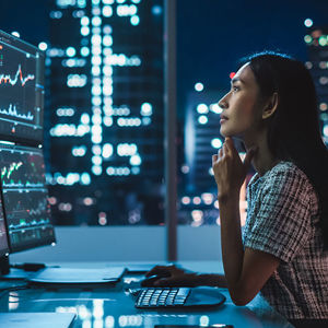 Woman Reviewing Data On An Array Of Monitors 