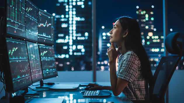 Woman Reviewing Data On An Array Of Monitors 